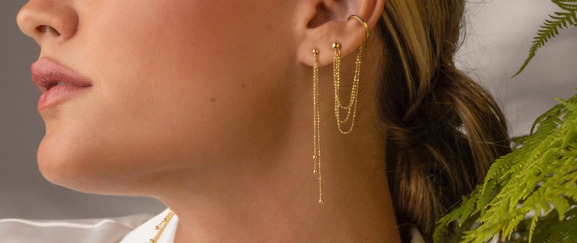 A close-up of a woman's ears wearing drop earrings