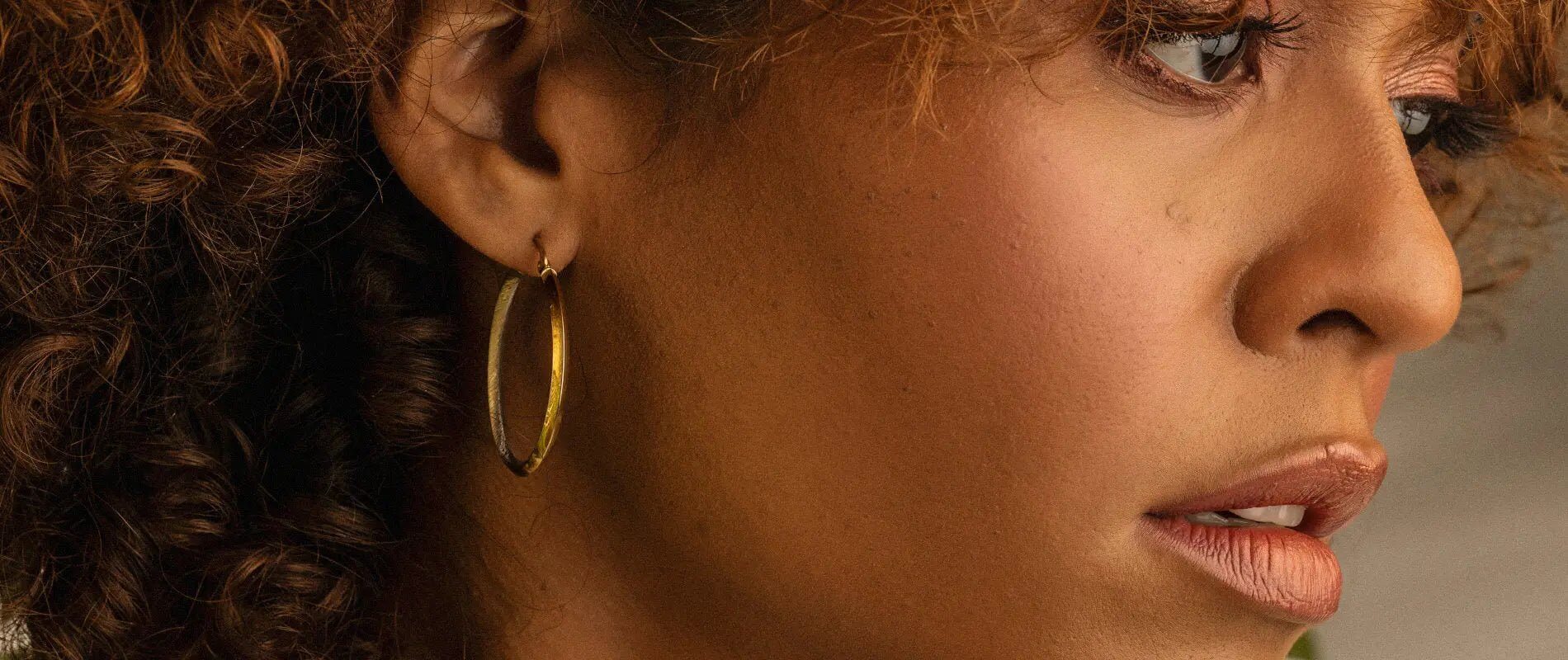 Close-up of a woman wearing elegant hoop earrings from the Gold Jewelry Collection.