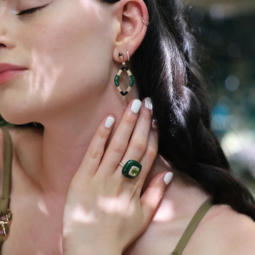 Close-up of a woman wearing a malachite ring and matching earrings, showcasing luxurious green gemstones.