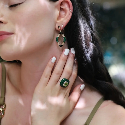 Close-up of a woman wearing a malachite ring and matching earrings, showcasing luxurious green gemstones.