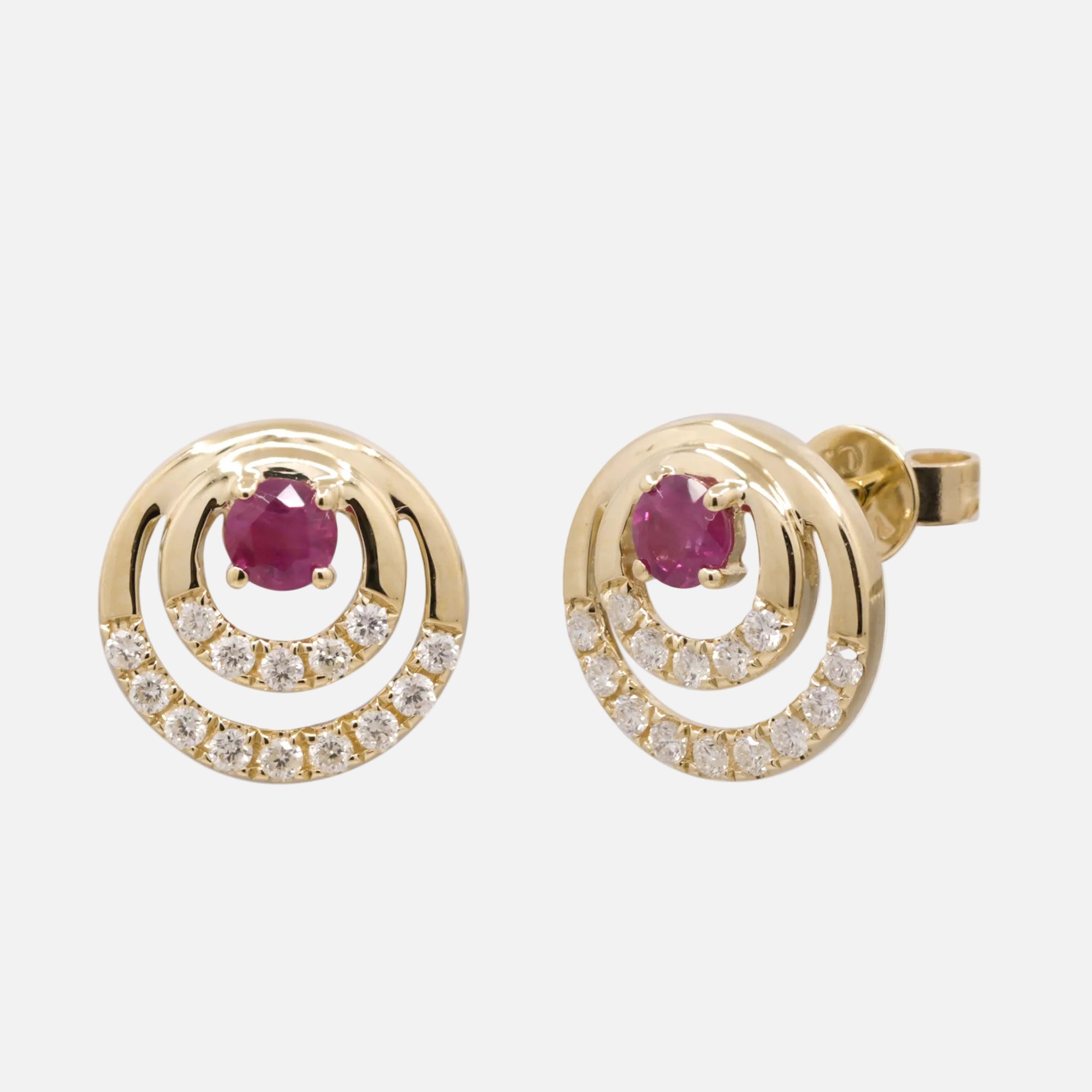 Ruby stud earrings featuring a round ruby center and sparkling diamond accents in a modern design.