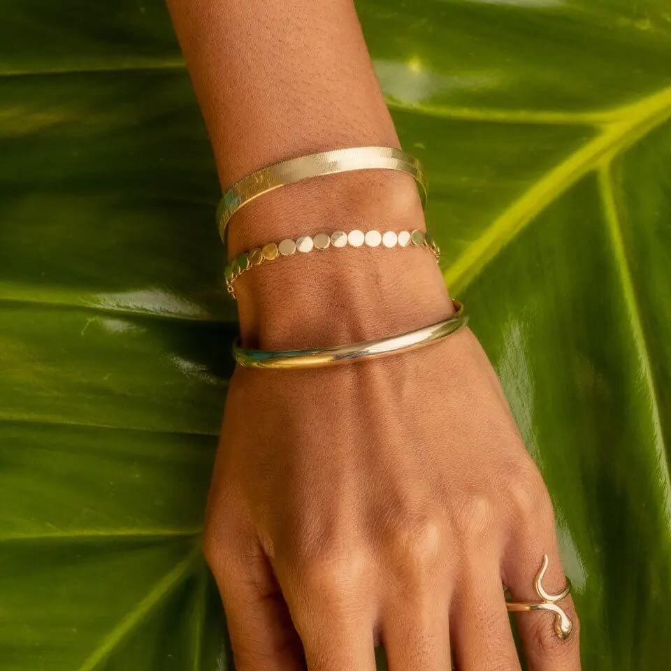 Elegant hand wearing three gold bangle bracelets, showcasing the beauty of gold bangle bracelet styles.